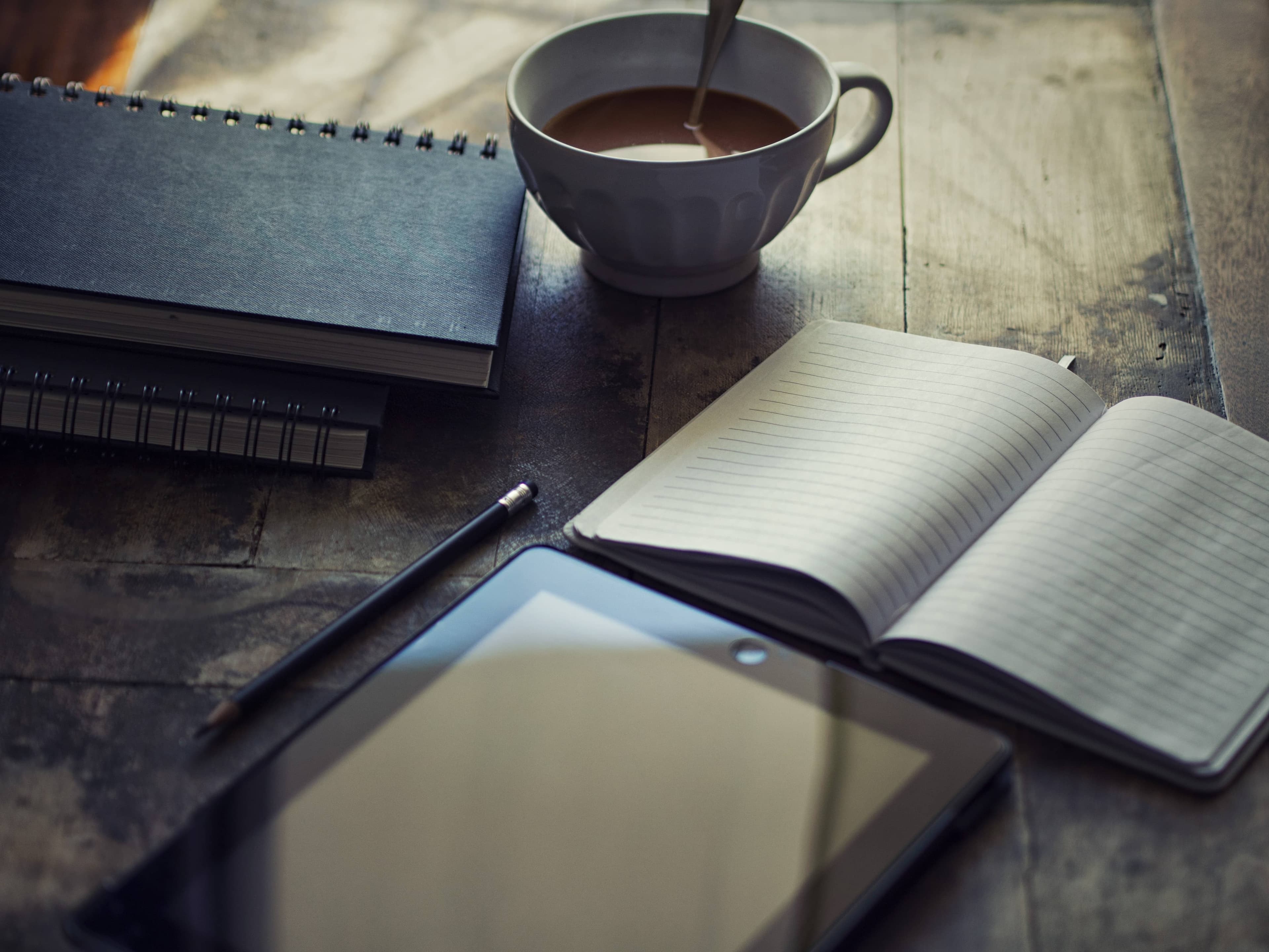 a cup of coffee, a journal, and a tablet
